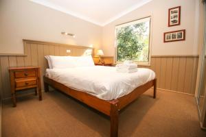 ein Schlafzimmer mit großem Bett und Fenster in der Unterkunft Autumn Leaf Cottage 1 in Harrietville