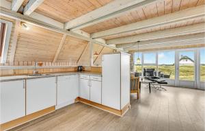 a kitchen with white cabinets and a table and chairs at Holiday Home Hvide Sande With A Fireplace 05 in Bjerregård +18 photos