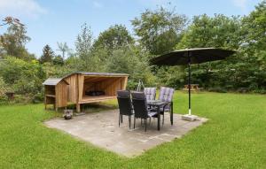 a table and chairs under an umbrella next to a dog house at Cozy Home In Glesborg With Wifi in Glesborg +19 photos