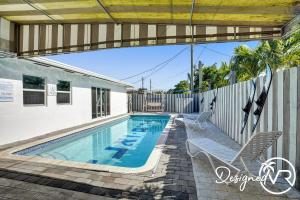 a swimming pool with two chairs and a fence at Modern condo wpool patio in Deerfield Beach