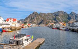 a boat is docked at a dock with houses and mountains at Amazing Home In Stamsund With Kitchen in Stamsund