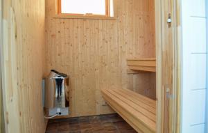a wood paneled bathroom with a trash can in a room at Awesome Home In Löttorp With Sauna in Löttorp