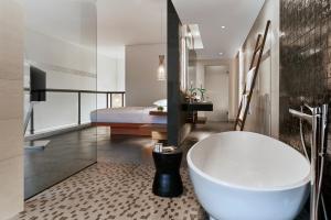 a bathroom with a bath tub and a bedroom at Renaissance Bali Uluwatu Resort & Spa in Uluwatu
