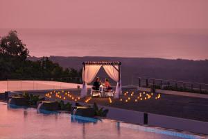 two people sitting at a table under a tent on a roof at Renaissance Bali Uluwatu Resort & Spa in Uluwatu