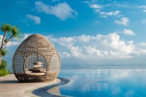 a wicker chair with two teddy bears sits next to a pool at Renaissance Bali Uluwatu Resort & Spa in Uluwatu