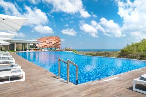 a pool at a resort with lounge chairs and the ocean at Renaissance Bali Uluwatu Resort & Spa in Uluwatu