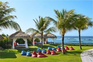 a row of red and blue chairs on the grass near the ocean at Renaissance Bali Uluwatu Resort & Spa in Uluwatu