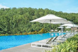 a swimming pool with white umbrellas and chairs next to it at Renaissance Bali Uluwatu Resort & Spa in Uluwatu