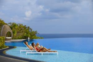 two women laying on lounge chairs in a swimming pool at Renaissance Bali Uluwatu Resort & Spa in Uluwatu