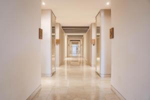 a corridor of a building with white walls and a long hallway at Amnaya Resort Kuta in Kuta