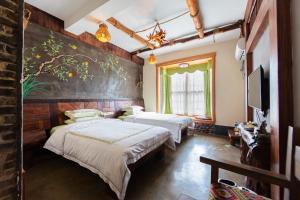 a bedroom with two beds and a painting on the wall at Butterfly Flowers Inn in Zhangjiajie