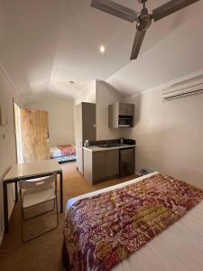 una camera da letto con un letto, un tavolo e una cucina di Parachilna Overflow Accommodation a Flinders Ranges