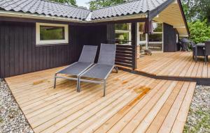 a wooden deck with two chairs on a house at Holiday Home Røllikevej Tranekær V in Skattebølle