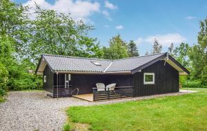 a black cabin with two white chairs in the backyard at Holiday Home Røllikevej Tranekær V in Skattebølle +12 photos