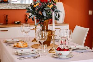 een tafel met borden en glazen en een vaas met bloemen bij La Bohème - VILLA PAULA in Istres