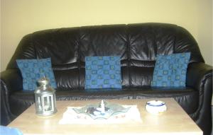 a black leather couch with blue pillows and a table at 1 Bedroom Amazing Apartment In Hohwacht in Hohwacht