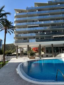 a hotel with a swimming pool in front of a building at Apartamento Elegance La Cala Benidorm in Benidorm
