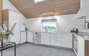 a kitchen with white cabinets and a wooden ceiling at Nice Home In Sydals With Sauna in Høruphav +14 photos