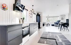 a kitchen with white and black appliances and a dining room at Three-Bedroom Holiday Home In Henne in Henne Strand
