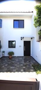 a white house with a black door and a courtyard at Queens Gardens Bliss in Paphos City