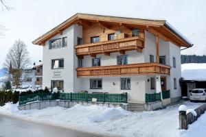 a house with a wooden balcony in the snow at Haus Jasmin in Ellmau