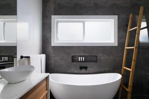 a bathroom with a white tub and a window at Austin Cottage - Pet friendly! in Merewether +4 photos