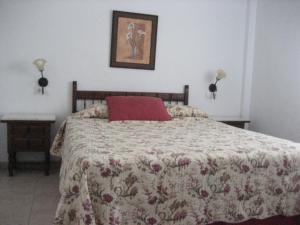 Un dormitorio con una cama con una almohada roja encima. en Residencial Augusta, en Islantilla