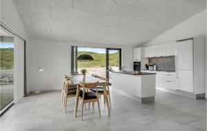 a kitchen with white cabinets and a table and chairs at Holiday Home Hvide Sande 25 in Bjerregård