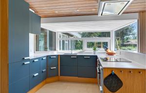a kitchen with blue cabinets and a large window at Gorgeous Home In Knebel With Sauna in Skødshoved Strand