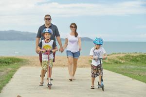 汤斯维尔BIG4 Tasman Holiday Parks - Rowes Bay的一名男子和两个孩子在人行道上骑滑板车