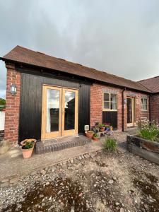 ein Backsteinhaus mit Pflanzentöpfen davor in der Unterkunft Rural cottage in Shropshire Hills in Leebotwood + 5 Fotos