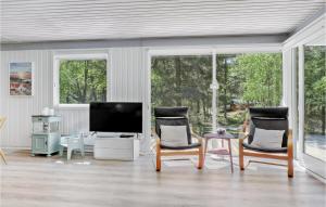 Una sala de estar con dos sillas y un televisor. en Holiday Home Nexo L, en Spidsegård