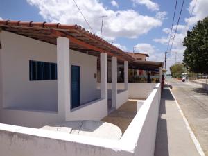 a white building with a white fence next to a street at Casa Mobiliada Galinhos in Galinhos