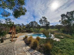 a swimming pool in a landscaped yard with a garden at the YellowBoxWood Heathcote - Echidna Ridge and Emu Valley Tents x 2 in Heathcote