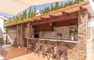 an outdoor kitchen with a bar with stools at 4 Bedroom Nice Home In Cómpeta in Acebuchal