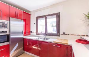 a kitchen with red cabinets and a stainless steel refrigerator at 4 Bedroom Nice Home In Cómpeta in Acebuchal
