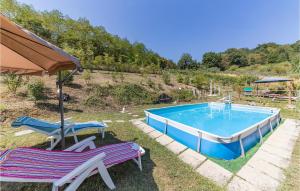 a swimming pool with two chairs and an umbrella at Casa Rosa in Terranuova Bracciolini