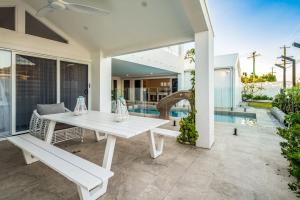 a white table and bench on a patio with a pool at Golden Beach Ultimate Family Getaway - Pool & Spa in Golden Beach
