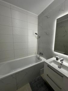 a white bathroom with a tub and a sink at Zenit Apartment Oradea in Oradea +7 photos