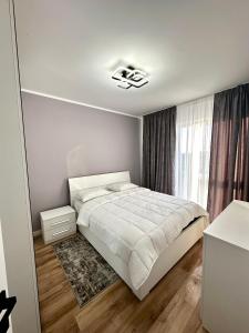 a white bedroom with a bed and a window at Zenit Apartment Oradea in Oradea