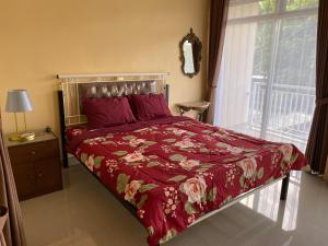 a bedroom with a bed with a red comforter and a window at Luchis HOME Ijen in Banyuwangi
