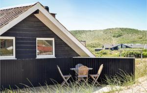 a black house with a table and chairs in front of it at Holiday Home Hvide Sande 20 in Bjerregård