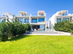ein großes weißes Haus mit einem Rasen davor in der Unterkunft Azure Breeze Villa - Roof Garden & Sea Views in Protaras