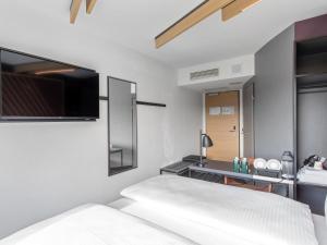 a bedroom with a bed and a tv on the wall at B&B Hotel Hamburg-Airport in Hamburg