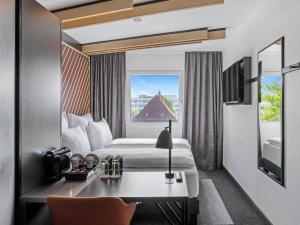 a hotel room with a bed and a desk and a window at B&B Hotel Hamburg-Airport in Hamburg