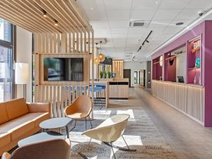 an office lobby with a couch and chairs at B&B Hotel Hamburg-Airport in Hamburg