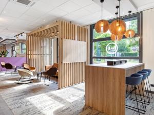a lobby of a restaurant with a bar and chairs at B&B Hotel Hamburg-Airport in Hamburg