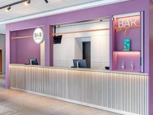 a bar with purple walls and a bar sign at B&B Hotel Hamburg-Airport in Hamburg
