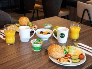 a table with plates of food and glasses of orange juice at B&B Hotel Hamburg-Airport in Hamburg