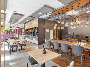 a dining room with tables and chairs and chandeliers at B&B Hotel Hamburg-Airport in Hamburg